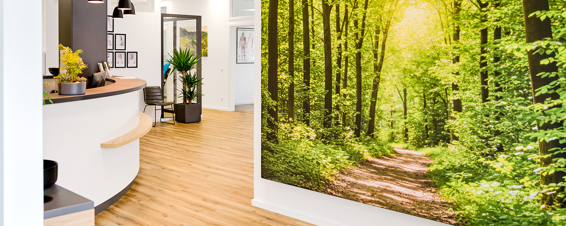 Eingangsbereich mit einem großen Waldbild und Blick auf die Rezeption.