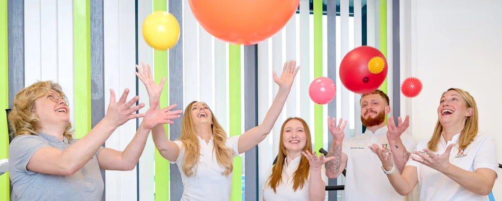 Mitarbeiterinnen versuchen lachend hochgeworfene Bälle aufzufangen.