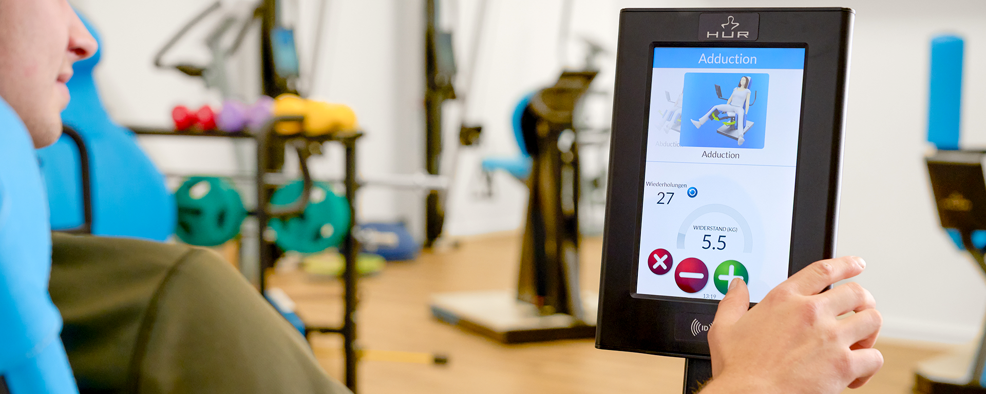 Ein junger Mann trifft seine Einstellungen auf dem Display des medizinischen Trainingsgeräts.