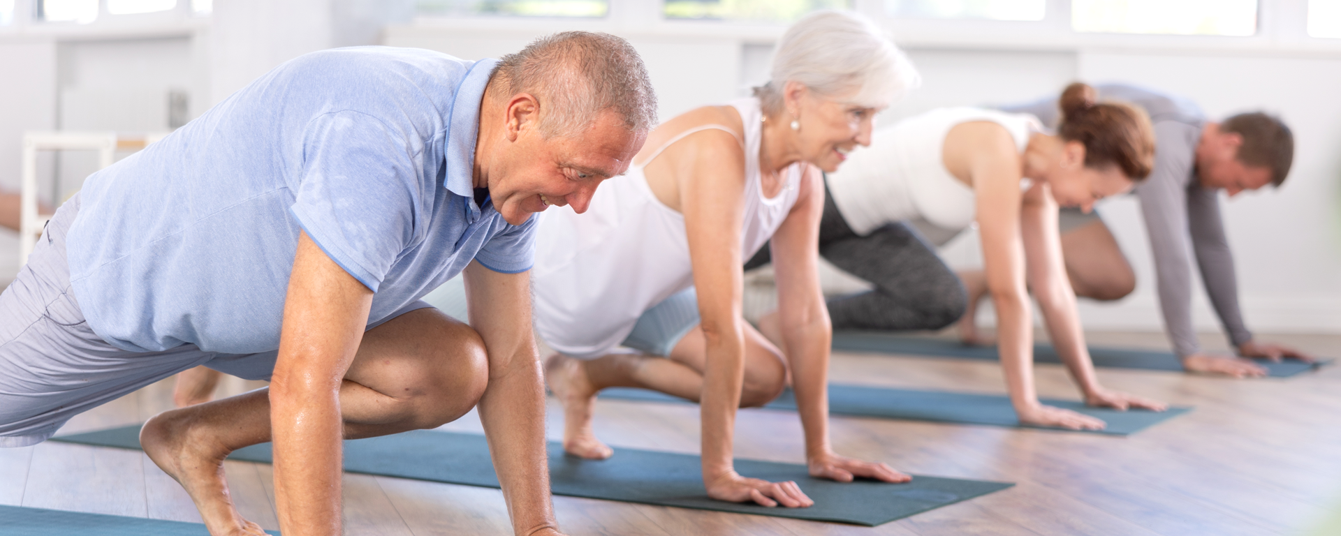 Männer und Frauen machen Übungen auf der eigenen Matte.